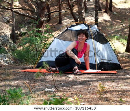 Summer in the Crimea. A happy woman near a tent reading a book