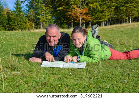 Happy hikers couple are having fun , when they are planning their route. Hikers are enjoying holiday  in autumn forest.