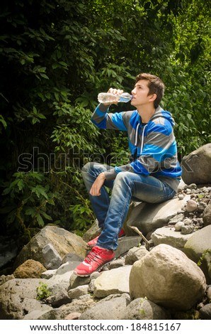 man drinking water outdoors in the jungle