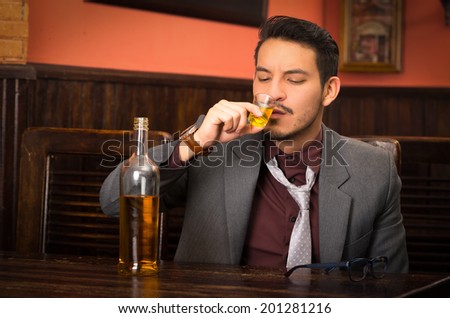 man in suit drinking alcohol shot in a bar