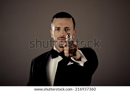Sexy man gangster agent criminal police in a tuxedo pointing a gun