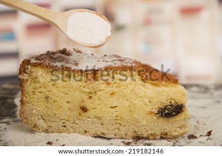 delicious piece of homemade vanilla cake decorated with caster sugar with wooden spoon on a wooden table