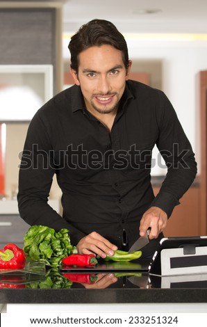 handsome young confident modern man cooking healthy recipe while using tablet