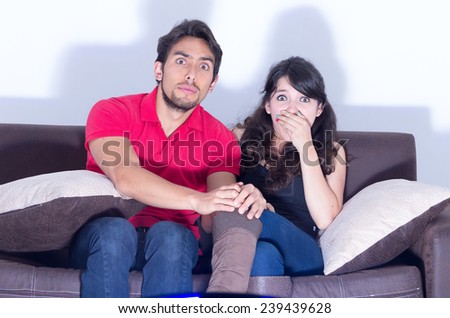 young attractive couple watching scary movie at home