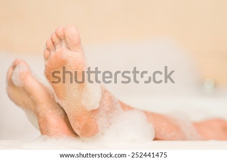 closeup of woman\'s feet covered with foam bubble bath