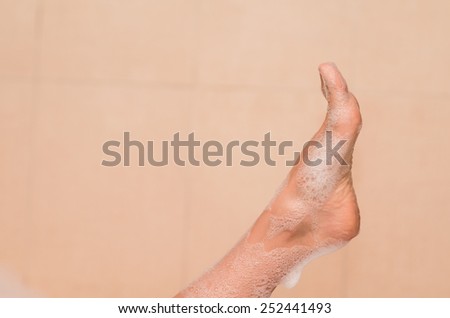 closeup of woman\'s foot covered with foam bubble bath