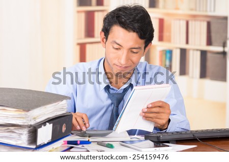 young stressed overwhelmed business man with piles of folders on his desk