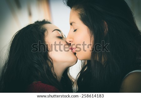 closeup portrait of cute lesbian couple in love kissing outdoors street view