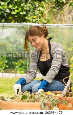 beautiful young woman kneeling on the grass enjoying gardening outdoors