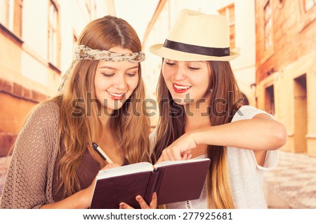 Beautiful college tourist girls checking travel book