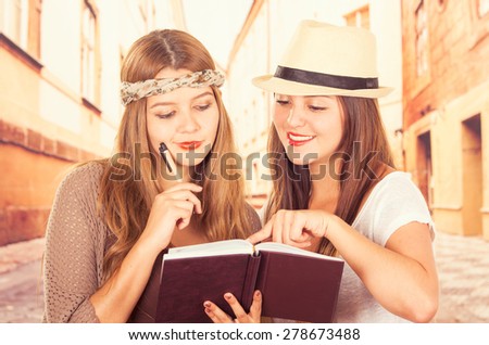 Beautiful college tourist girls checking travel book