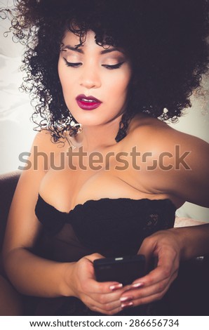 closeup of girl in lingerie sitting on sofa playing with phone
