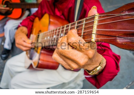 ARMENIA, COLOMBIA - FEBRUARY 23, 2015: Close up to hands of an indigenous man playing guitar in the central plaza of Armenia, Colombia