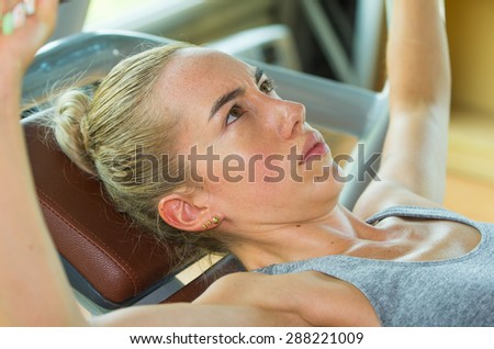 Fit womans face training on a benchpress with focused faceal expression
