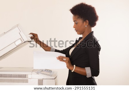 Black office woman lifting up lid of copy machine and holds a paper in other hand