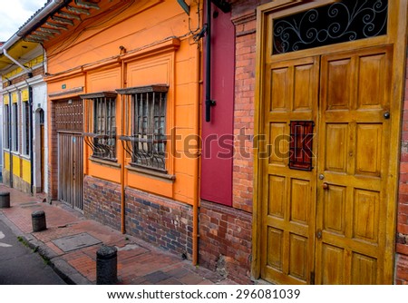 BOGOTA, COLOMBIA - FEBRUARY 9, 2015: Wooden entrance door next to barred windows and colorful walls on streetlevel typical for small townhouses in the old part of Bogota