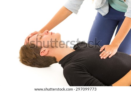 Couple demonstrating first aid techniques with male patient seemingly unconscious and female hands on head plus chest.