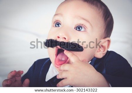 Cute beautiful baby boy in costume with mustache and suit white background close up
