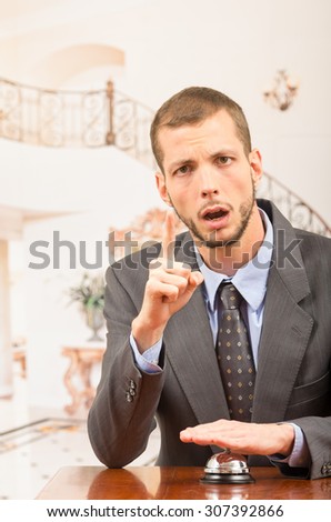 Upset guest businessman customer ringing hotel bell in reception desk demanding attention close up