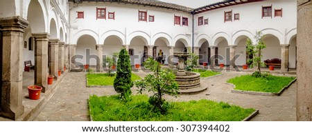QUITO, ECUADOR- AUGUST 4, 2015: Backyard of San Diego church showing small cozy garden with green plants and stone fountain typical spanish colonial style.