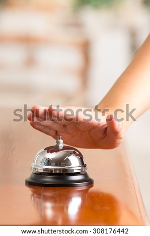 hand ringing hotel bell in reception desk close up selective focus