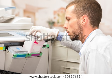 closeup shot of young male technician changing color cartridge toner in digital photocopier machine