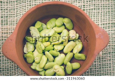 lima beans inside ceramic terracota bowl and rustic background.