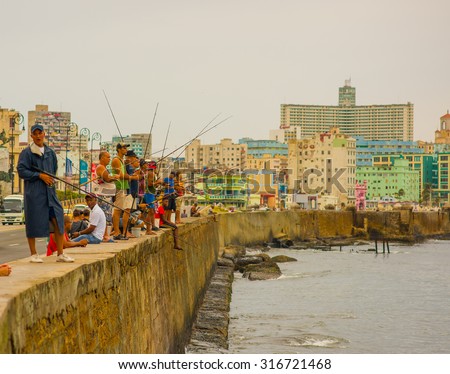 HAVANA, CUBA - AUGUST 30, 2015:  Local men fish on the sea in the city of Havana, Malecon quay. Fishing is a common hobby in Cuba.