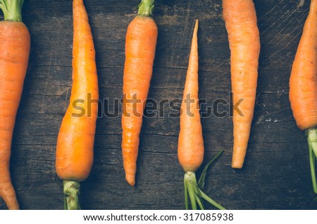 all-natural carrots lined up on wooden board rustic concept.