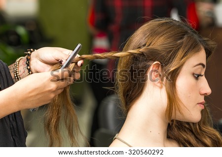 Closeup stylist hands working with brunette hair making a twist.