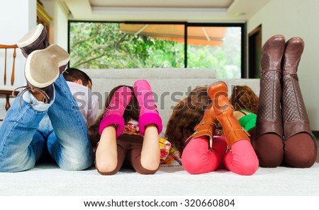 Family of four lying down facing away from camera with feet up in air.