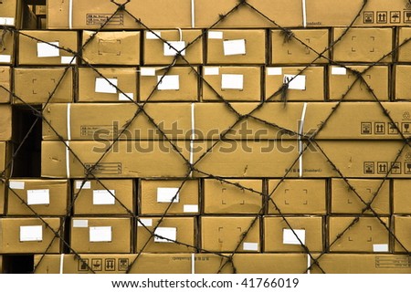 Multiple yellow cargo boxes with white address labels covered by secure netting abstract background.