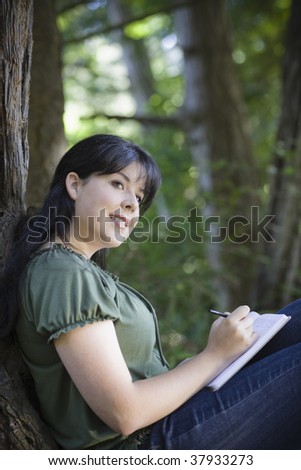 Young Woman In Woods Writing in Journal Looking Away from Camera