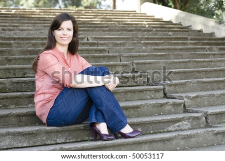 Pretty Young Woman Sitting Outside on Steps With Legs Crossed