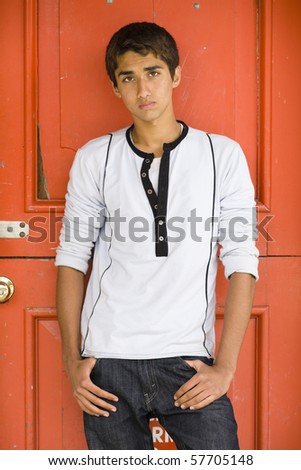 Teenage Indian Boy Standing With Hands in Pockets in Front of a Red Door