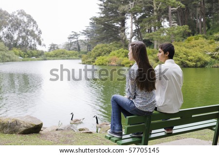 Two Teenagers Sitting on a Park Bench Looking at The Water