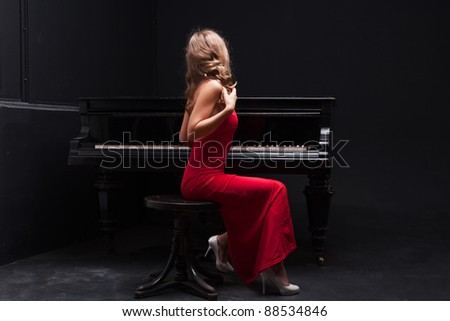 beautiful young attractive woman in evening dress and piano