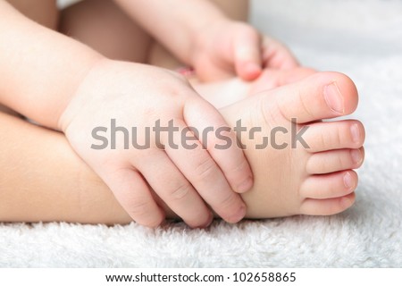 Baby feet and hands on the white soft cover