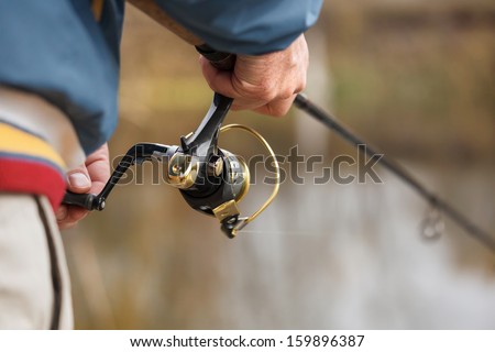 Closeup of Fisherman`s hand with spinning - autumn fishing season.