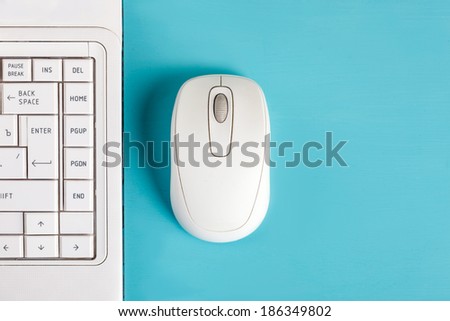 White mouse and laptop keyboard on table - top view.