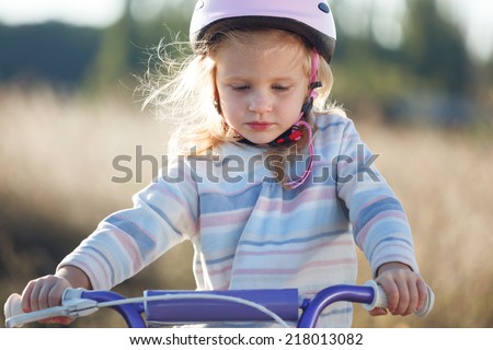 Small funny kid riding bike with training wheels.