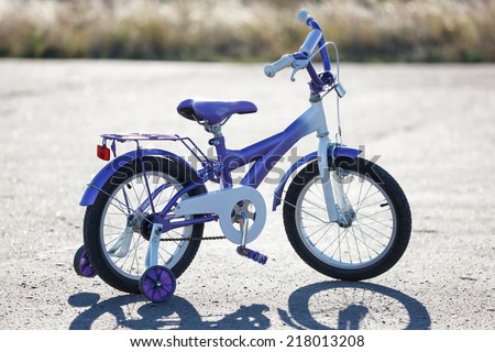 Small kids bike with training wheels outdoors.