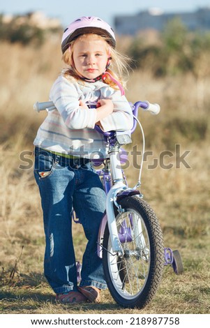Small funny kid riding bike with training wheels.