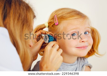 Pediatrician doctor examining little girl`s ears.