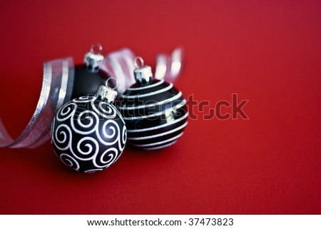 Black and White Christmas Baubles with Silver Ribbon on Red background.