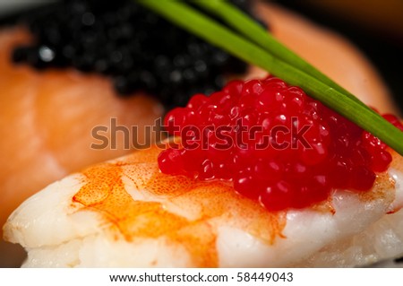Smoked salmon and prawn nigiri and norimaki sushi garnished with red and black fish eggs and chives.