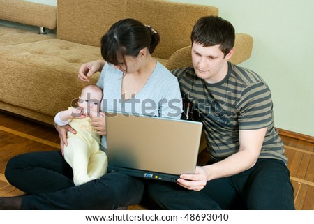 happy family home: father, mother and baby working on laptop