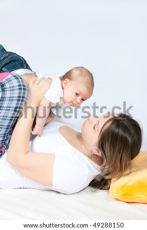 happy family home: mother and baby lying on the bed and playing