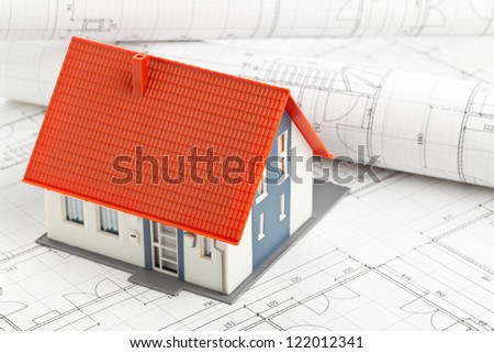 Model house on construction blueprints layed out on table