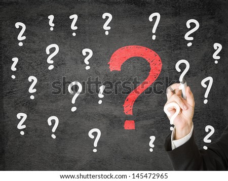 Businessman drawing question marks on transparent display